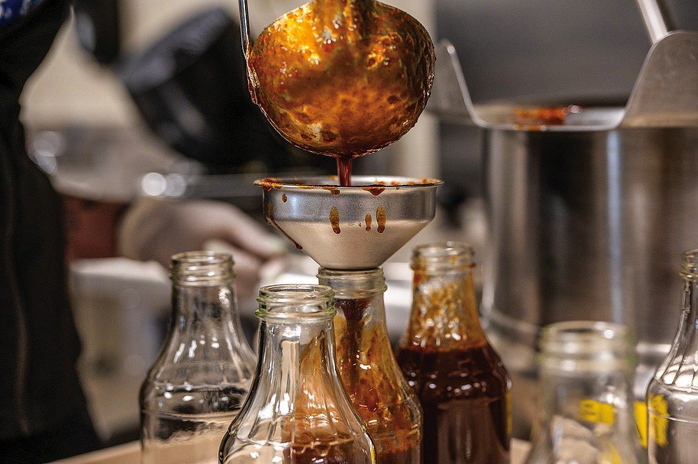 Pouring Papoo's BBQ Sauce into glass bottles