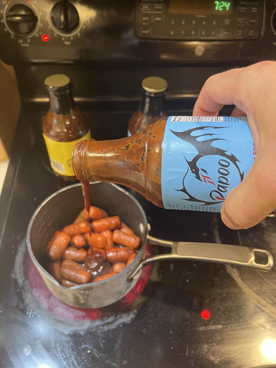 Pouring Papoo's Dragon's Breath over cocktail wieners on the stove