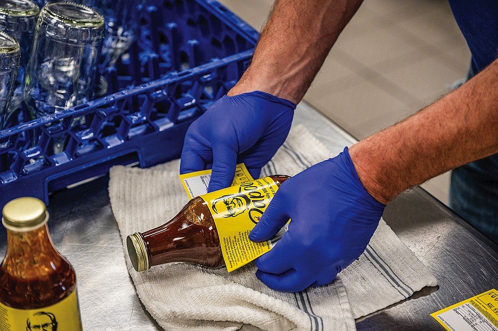 Labeling bottles of Papoo's BBQ Sauce by hand