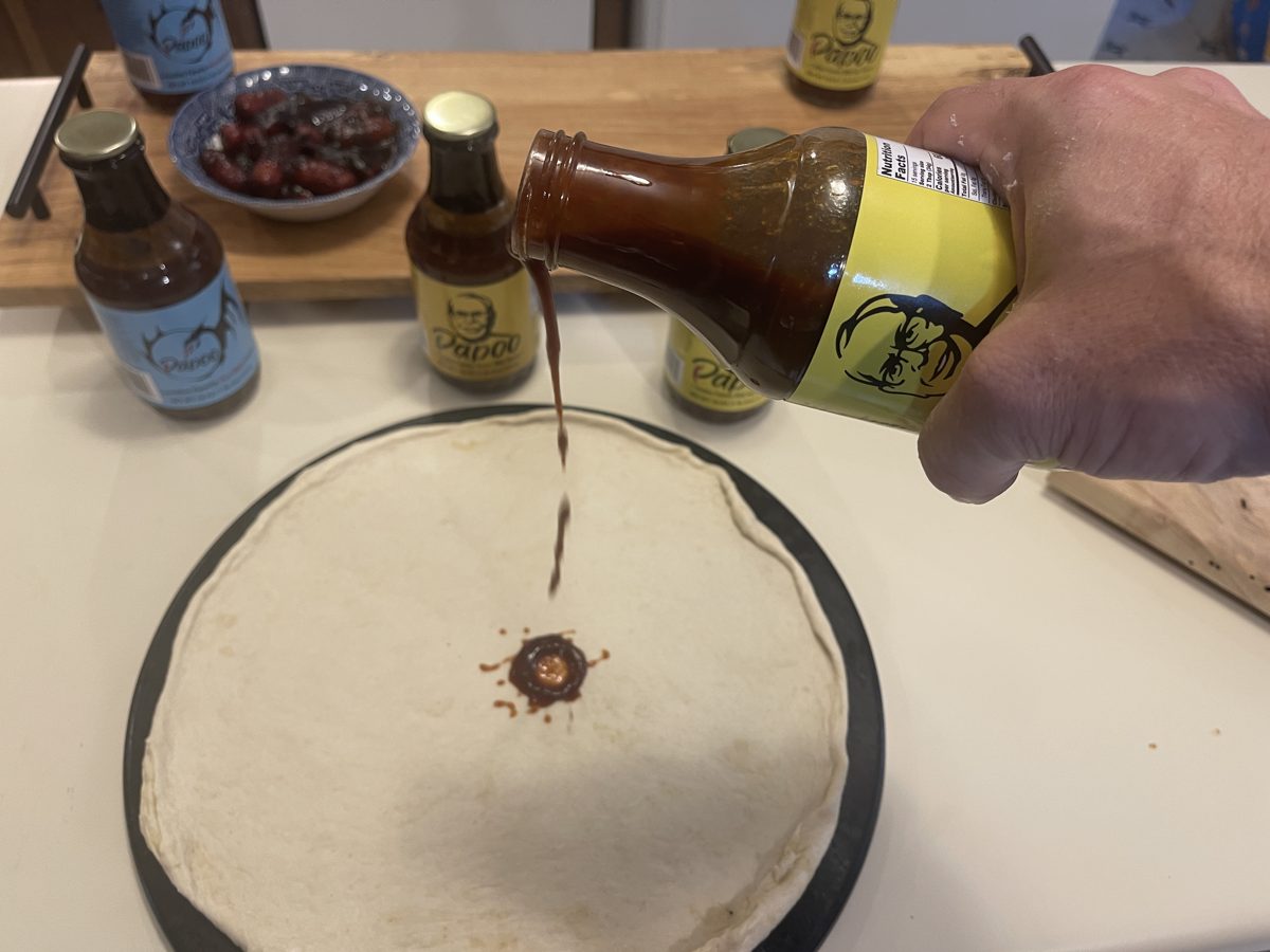 Pouring Papoo's BBQ Sauce onto the pizza dough