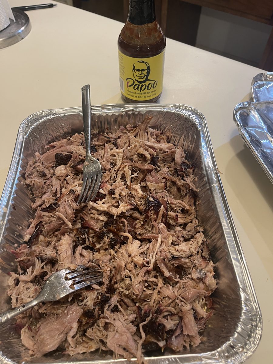 A pan of pulled pork with a bottle of Papoo's