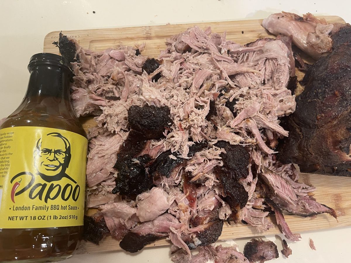 Pulled pork on a cutting board with Papoo's BBQ Sauce