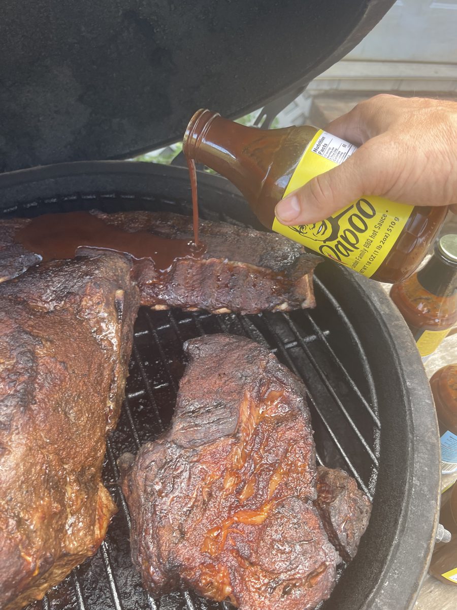 Brushing Papoo's BBQ Sauce onto ribs on the grill