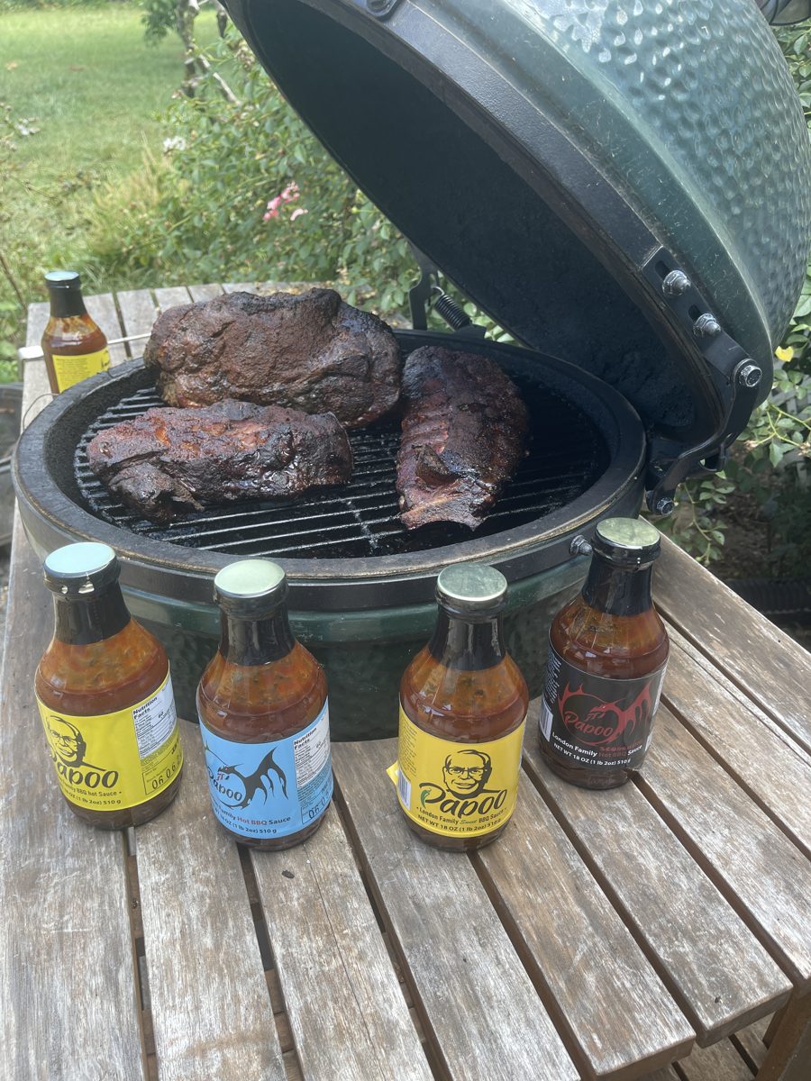 Smoked ribs and pork on the grill with all four Papoo's sauces on the table